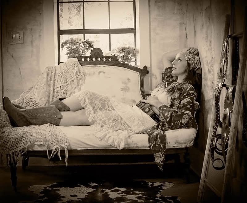 Darcy resting on a vintage settee in lace and boots